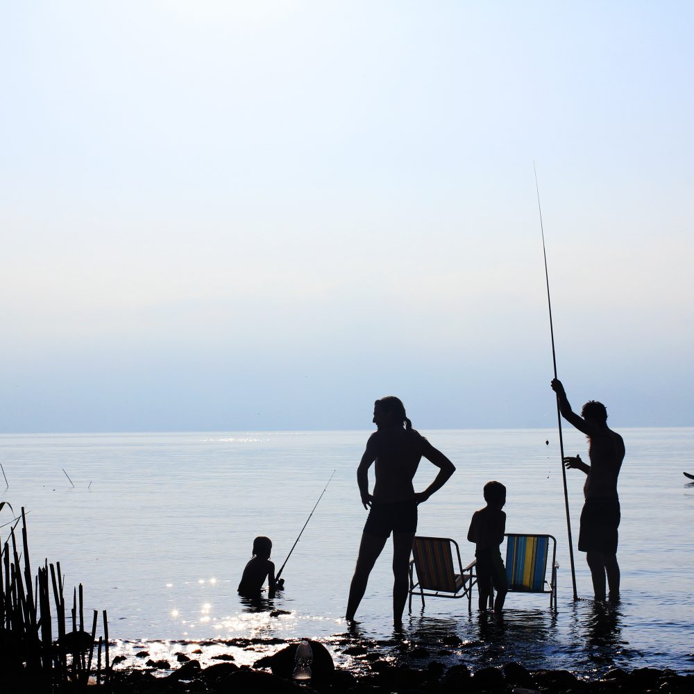 Personas pescando y acampando al lado de un lago